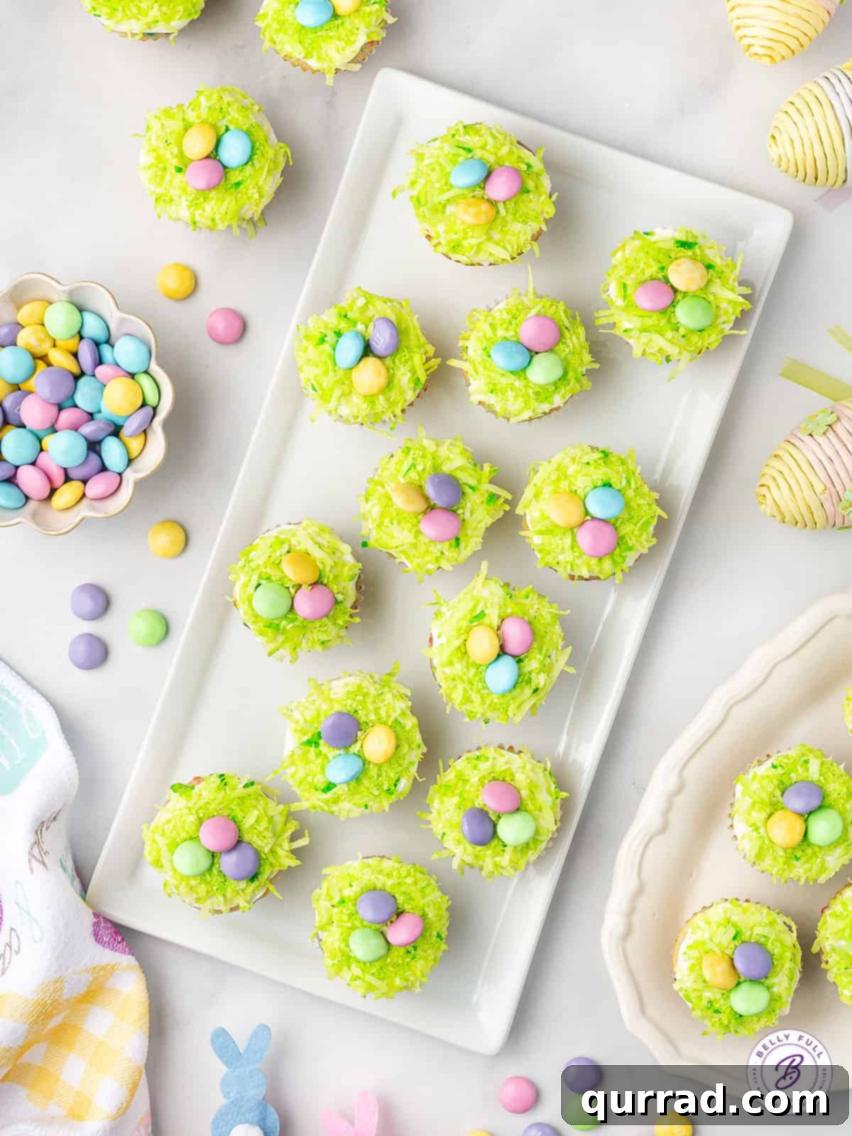 Hoppy Easter Mini Sprinkle Cupcakes 3 An overhead view of a platter showcasing Mini Easter Cupcakes, beautifully decorated with green dyed coconut and an assortment of pastel M&Ms.