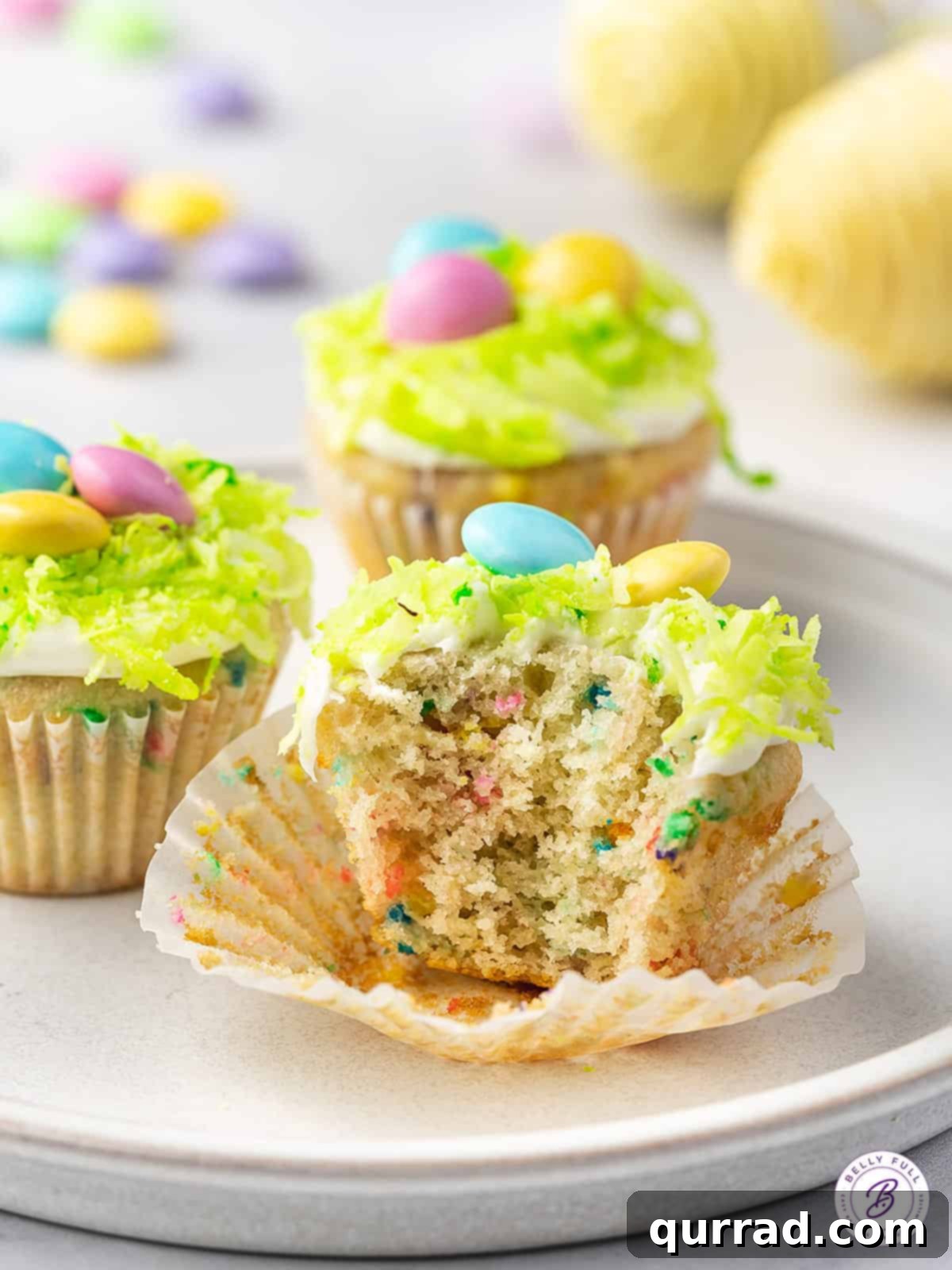 Hoppy Easter Mini Sprinkle Cupcakes 4 A single Mini Funfetti Cupcake placed in its paper liner, with a small bite taken to reveal its colorful interior.