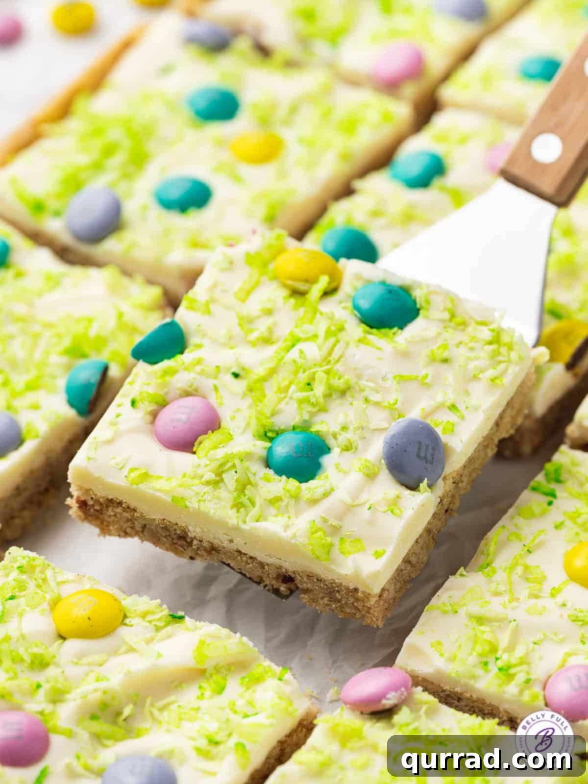 An Easter Sugar Cookie Bar being lifted off a serving spatula, showcasing its thick frosting and festive decorations.