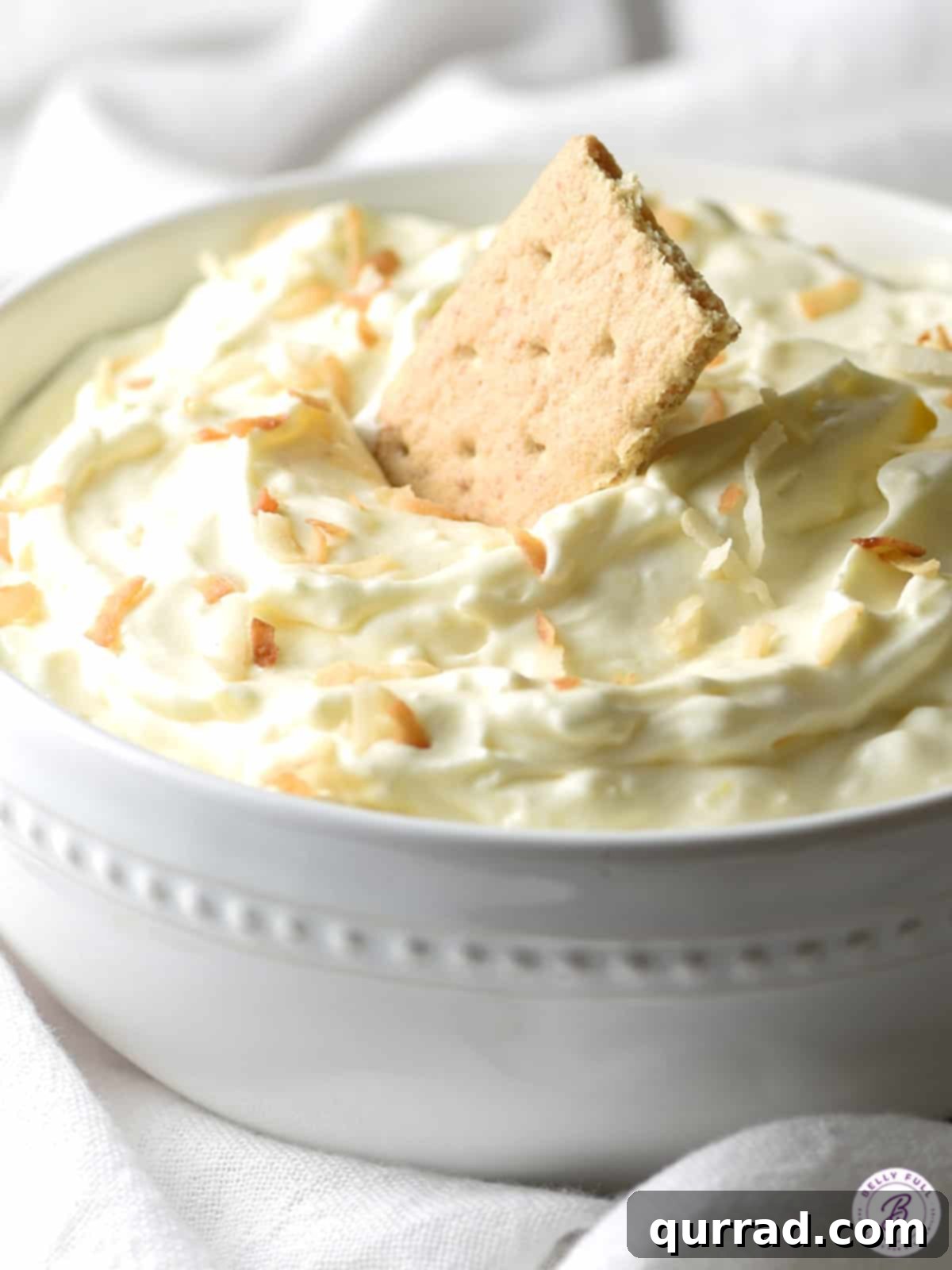 Creamy Coconut Dream Dip 4 A full bowl of coconut cream pie dip, ready to be served with a pile of graham crackers next to it.