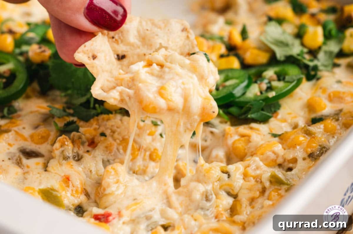 Golden Corn Goodness 9 A corn chip scooping hot, cheesy corn dip from a larger serving dish.