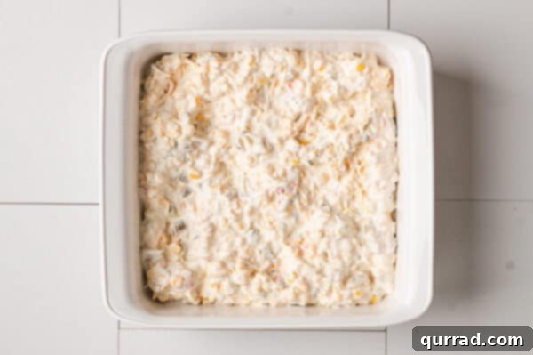 Unbaked creamy corn dip mixture in a casserole dish, ready for the oven.