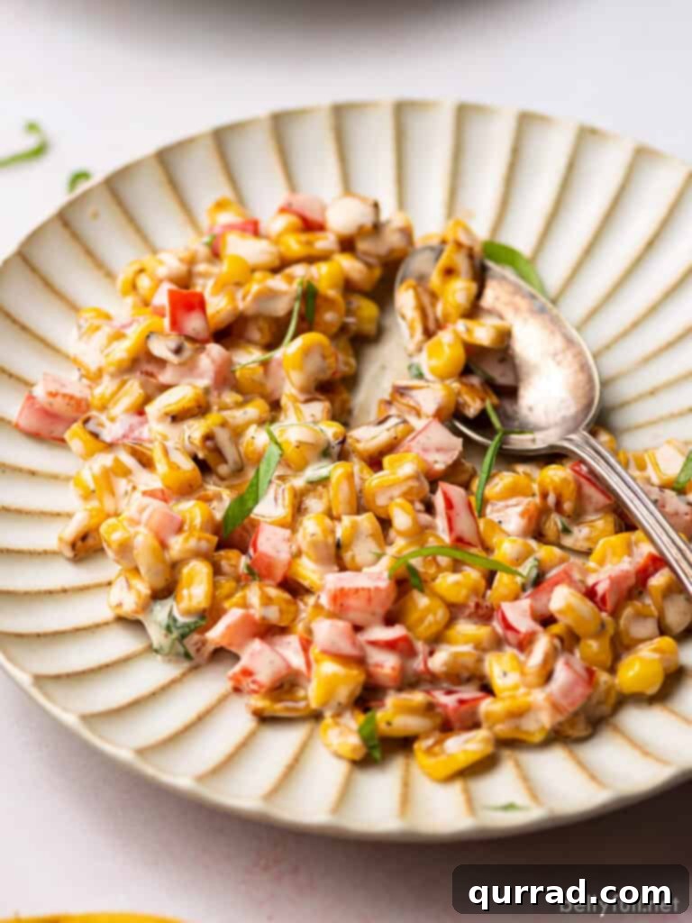 Vibrant Summer Corn Salad 2 Grilled corn, red bell pepper, and fresh basil combined in a vibrant summer salad on a plate.