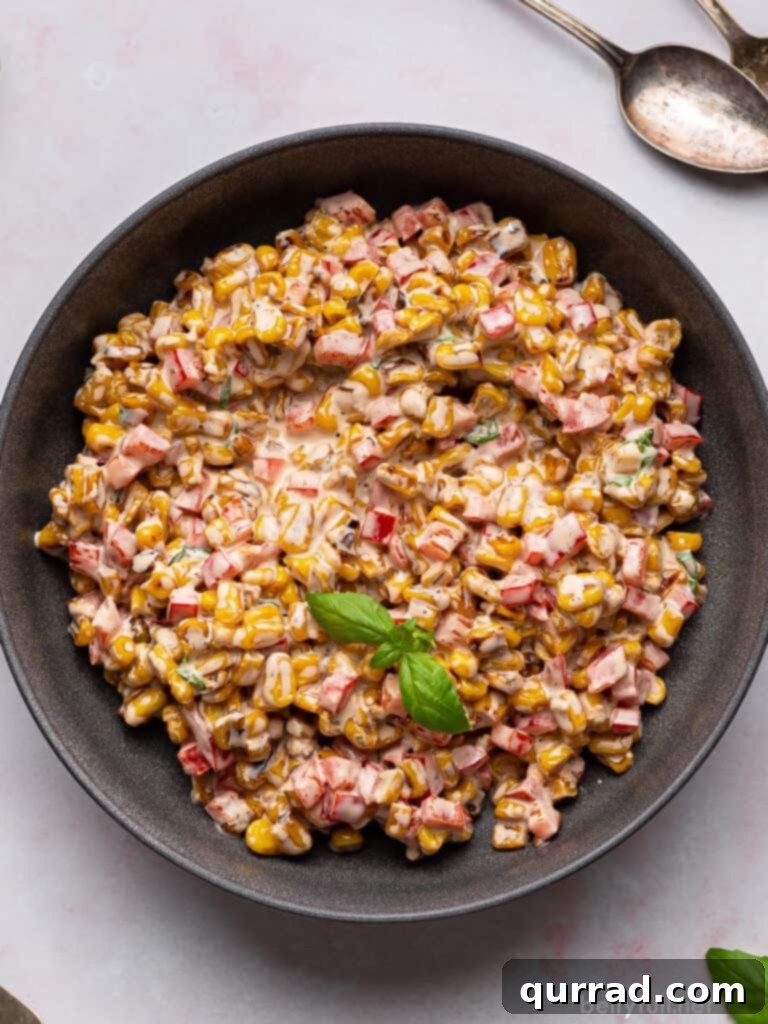 Vibrant Summer Corn Salad 3 Overhead view of a creamy corn salad generously coated in dressing, served in a black bowl.