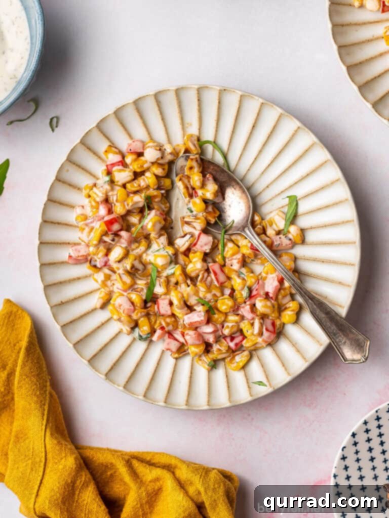Vibrant Summer Corn Salad 4 Overhead shot of creamy summer corn salad served on an ornate plate with a spoon, ready to be enjoyed.
