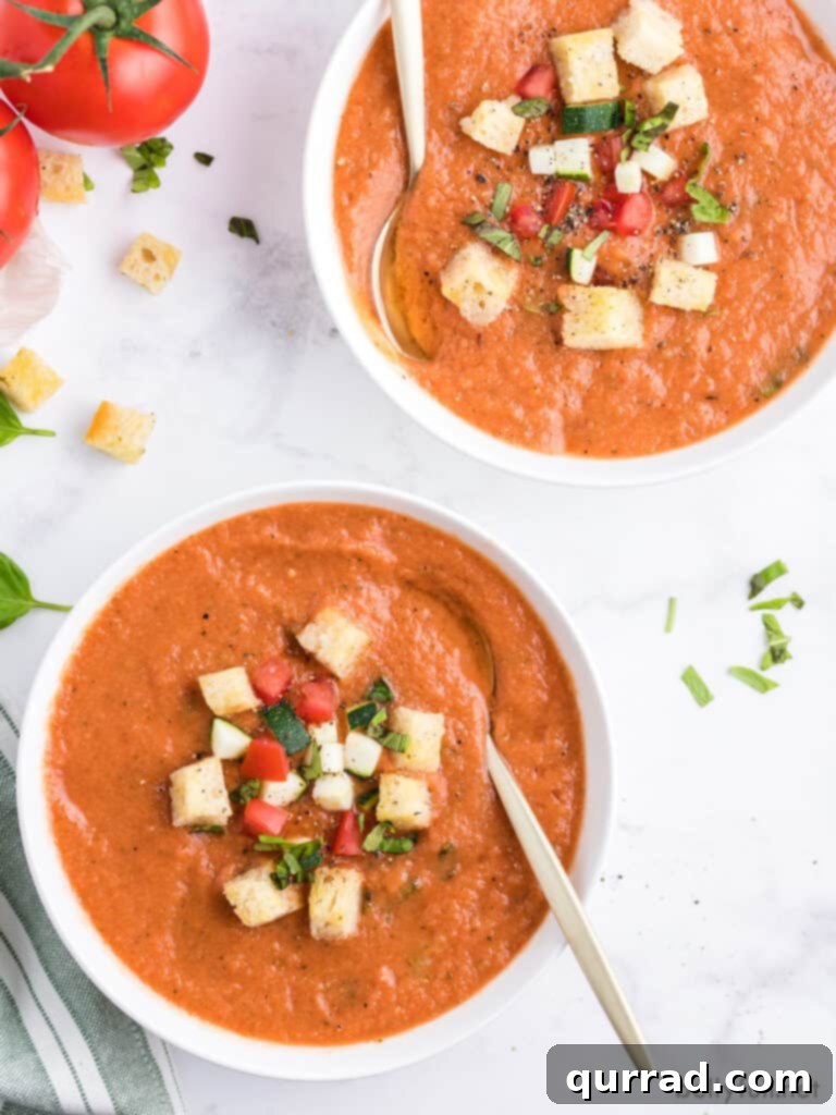 2 white bowls filled with garden vegetable soup and topped with croutons