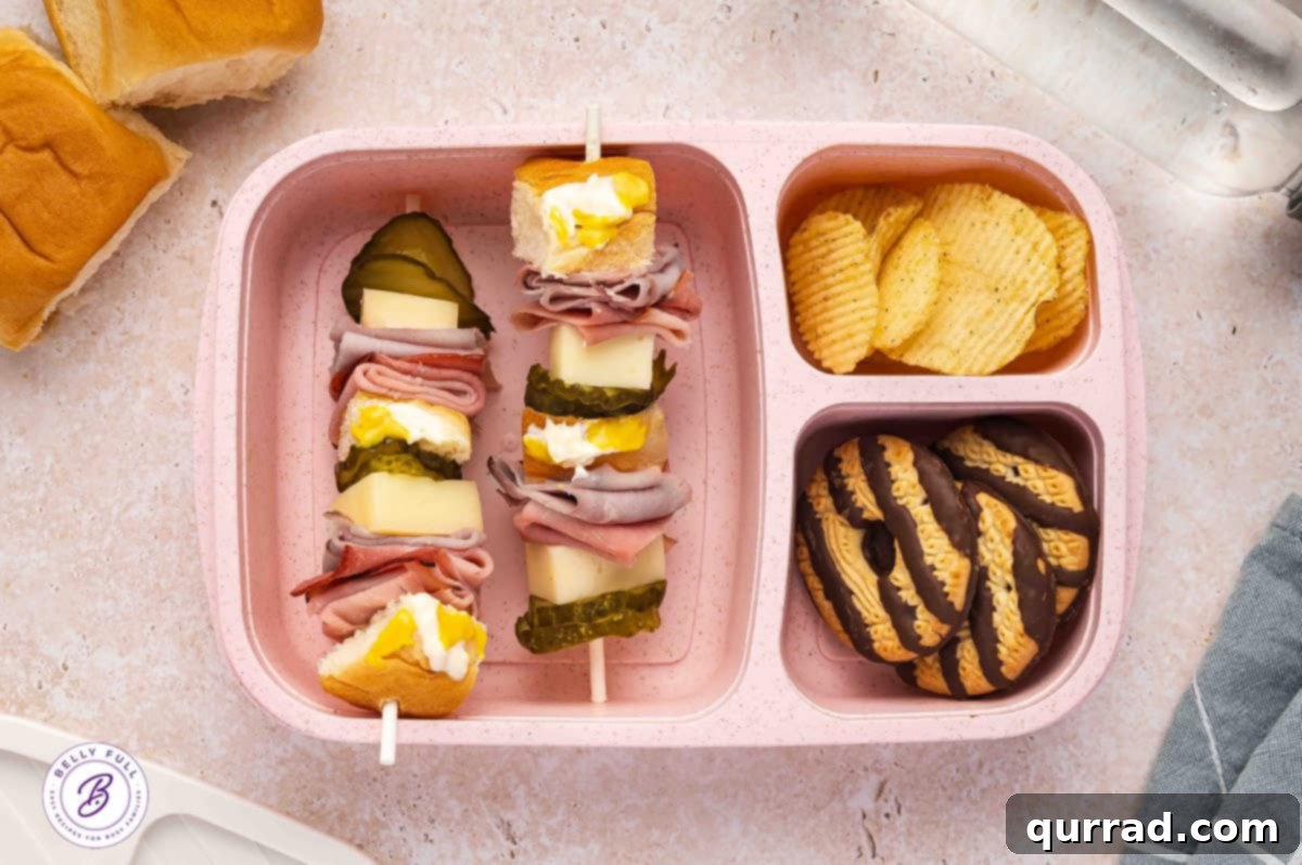Skewered Sandwich Classics 13 Cubano sandwich on a stick with Hawaiian rolls, sliced ham, sliced cooked pork, Swiss cheese, and dill pickle hamburger chips in a lunchbox.