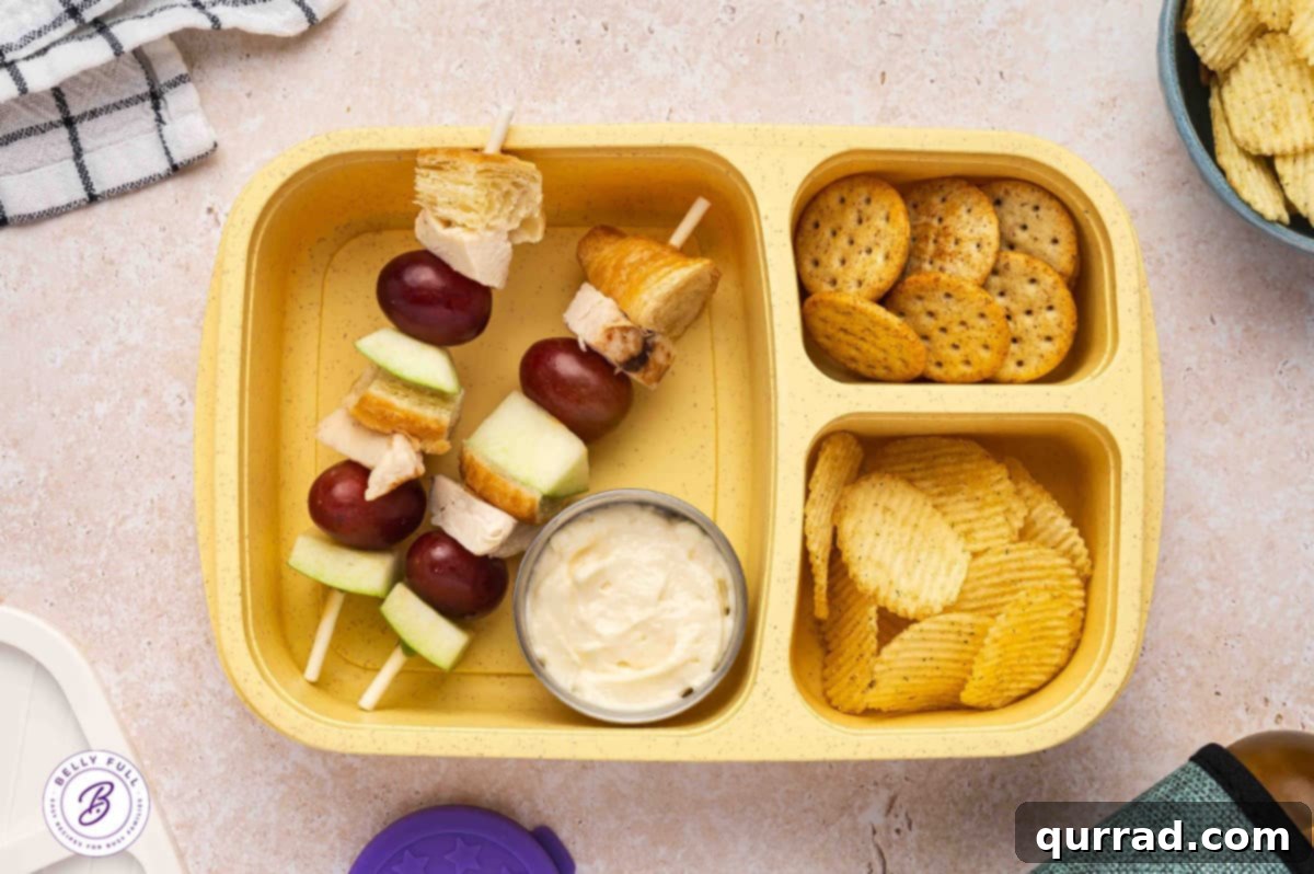 Skewered Sandwich Classics 4 Chicken Salad on a stick with croissant pieces, chicken, red grapes, and green apple in a lunch box, ready for a delicious meal.