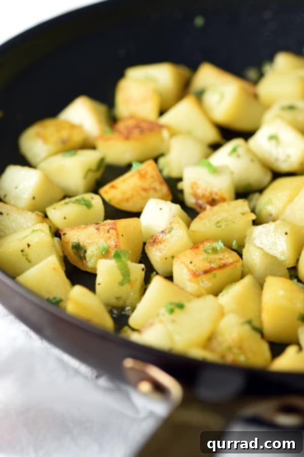 Close-up shot of sautéed crispy apples and potatoes cooking in a pan, showing golden brown edges.