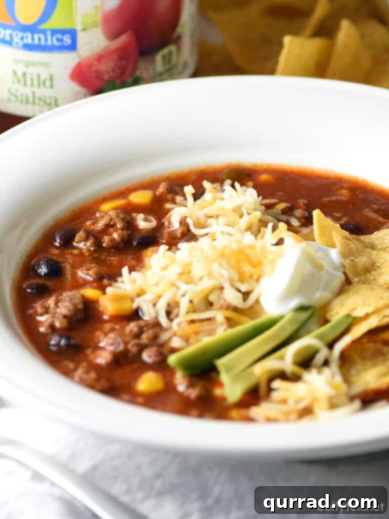 bowl of taco soup garnished with sliced avocado and sour cream