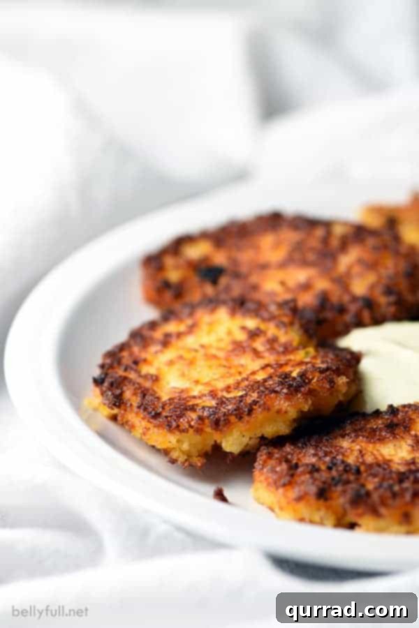 Delicious Potato and Carrot Latkes for Holidays Golden brown Potato Carrot Latkes piled high on a white serving plate, garnished with fresh herbs and a side of applesauce.