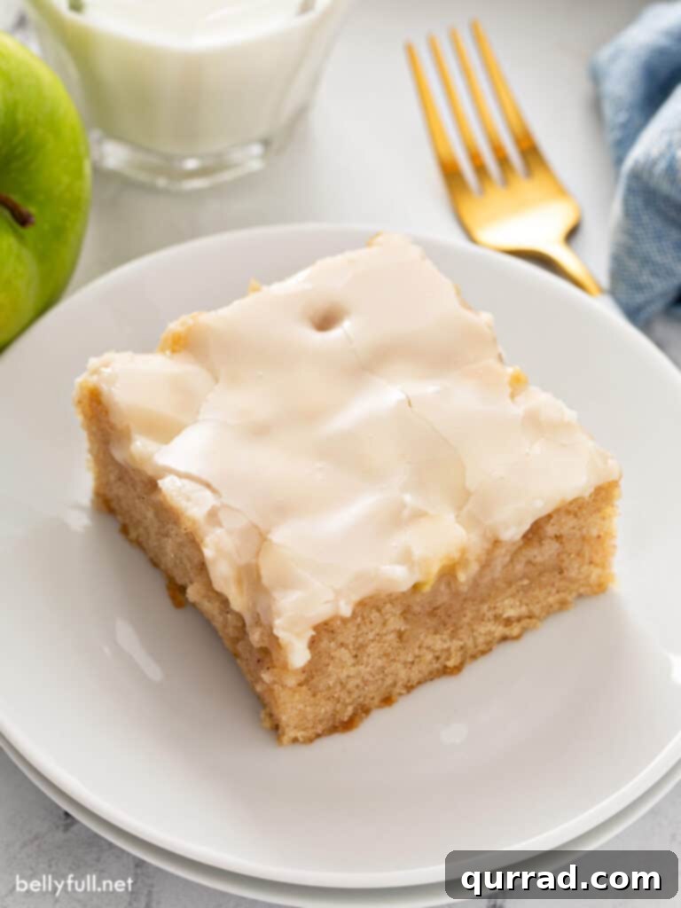 Autumn Apple Caramel Slab 2 A perfectly square slice of caramel apple sheet cake, glistening with caramel icing, served on a white plate, ready to be enjoyed.