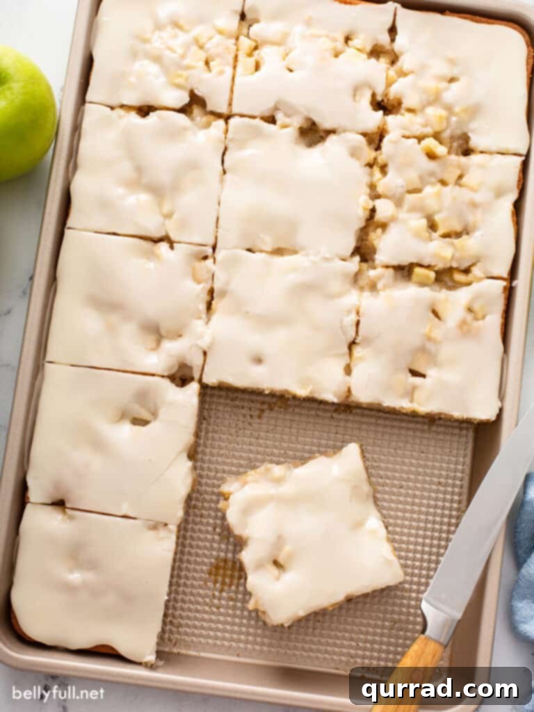 Autumn Apple Caramel Slab 3 A sheet pan of freshly baked caramel apple cake, cut into neat squares, showcasing the tender crumb and generous apple pieces within, ready for serving.