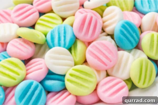 A close-up view of vibrant pink, blue, green, and white cream cheese button mints, highlighting their individual details and appealing colors.