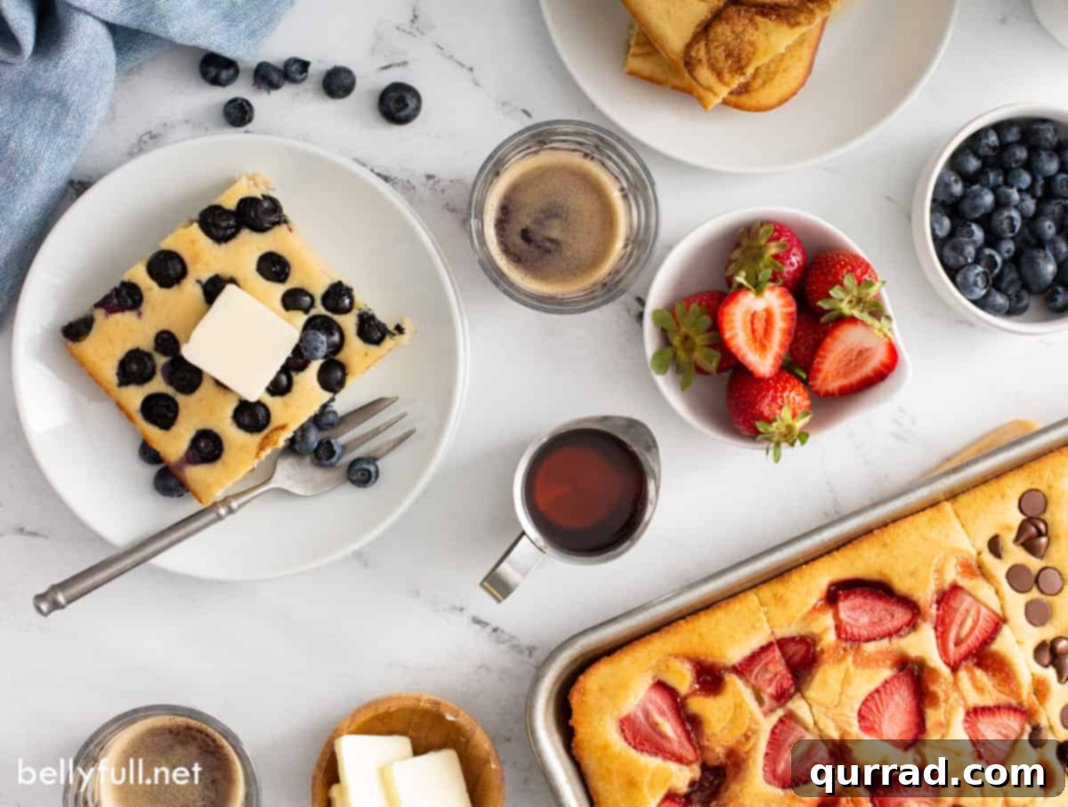 Beautifully arranged sheet pan pancakes with a side bowl of fresh strawberries and blueberries, ready for a wholesome breakfast.