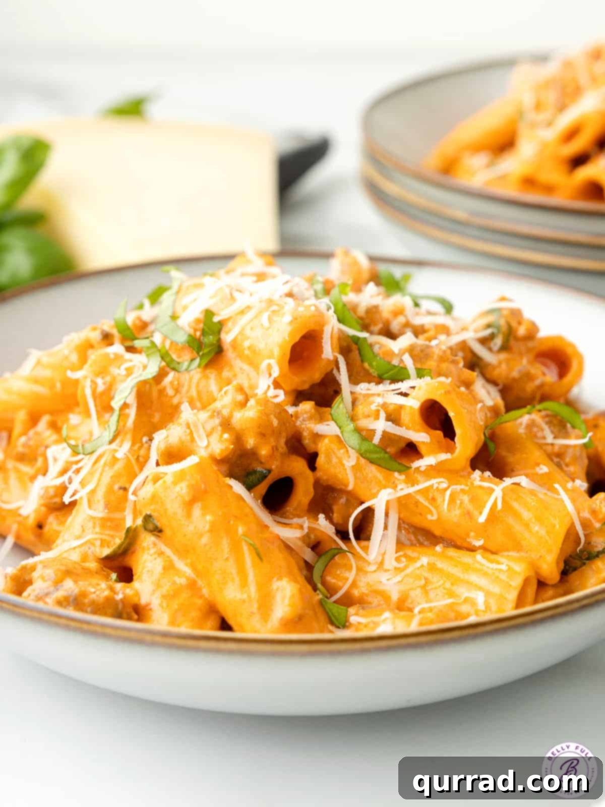 Effortless One-Pan Sausage Pasta 4 Close-up of creamy sausage pasta on a plate, garnished with basil and parmesan
