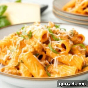creamy sausage pasta on plate with parmesan and basil