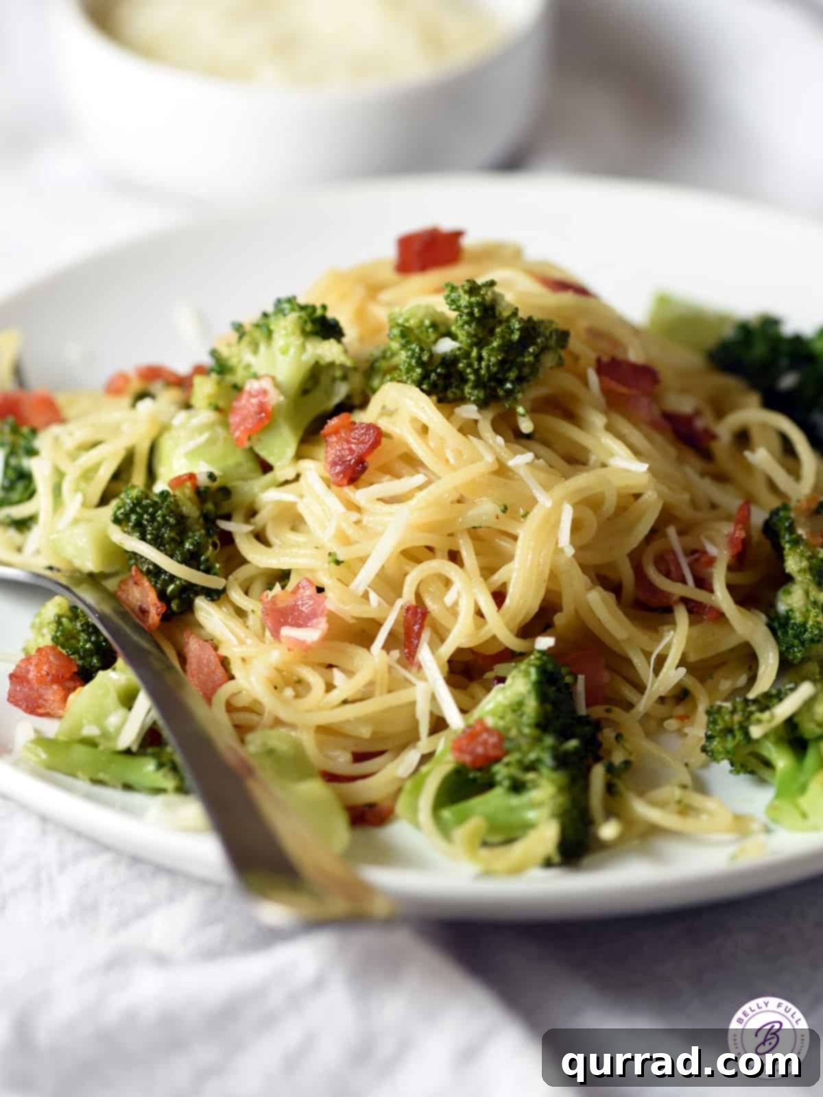 Bacon Broccoli Bliss Pasta 2 A generous serving of One-Pot Bacon and Broccoli Pasta on a white plate, showcasing crispy bacon bits, bright green broccoli florets, and delicate angel hair pasta coated in a savory sauce.