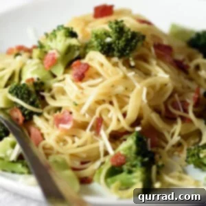Close up view of the finished One-Pot Bacon and Broccoli Pasta, generously topped with fresh Parmesan cheese and showing the texture of bacon, broccoli, and pasta.