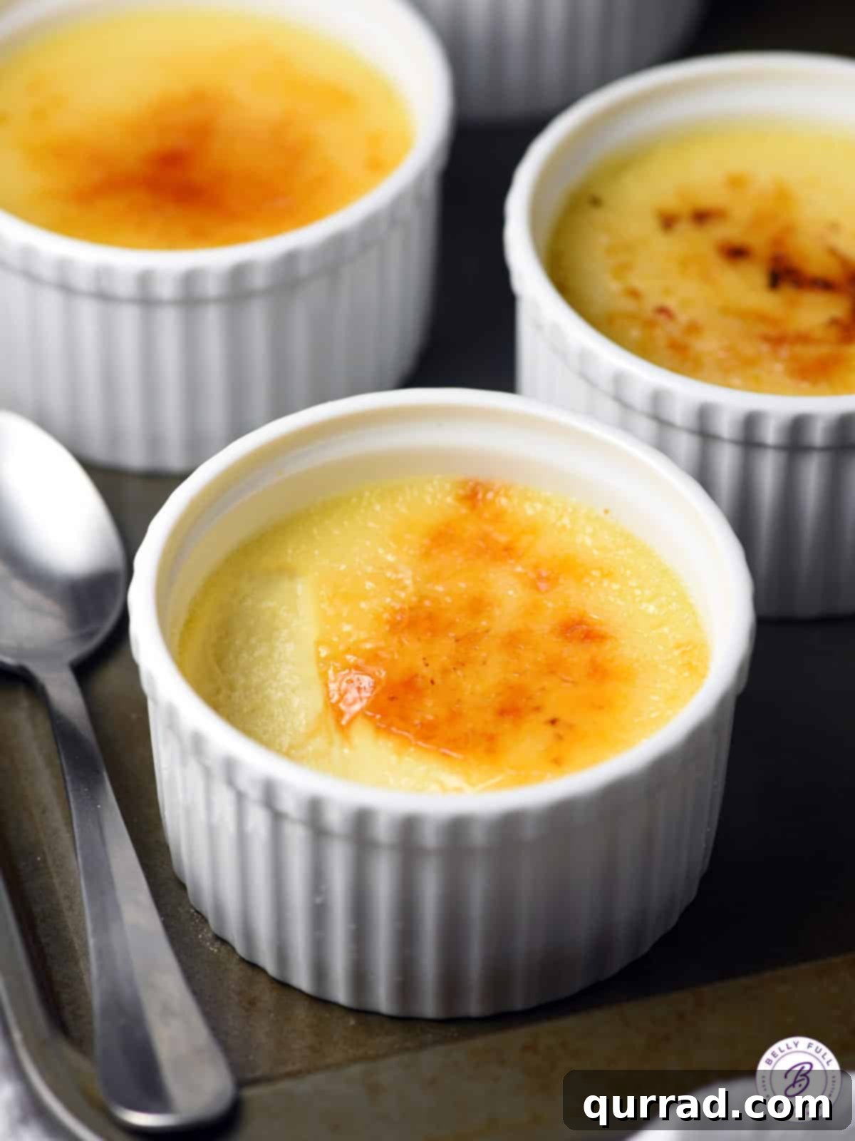 Slow Cooked Creme Brulee Dream 4 Four white ramekins filled with Slow Cooker Creme Brulee, perfectly caramelized, arranged on a serving tray