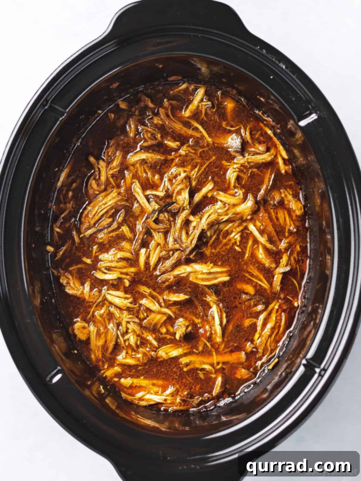 Set-and-Forget BBQ Chicken 4 An overhead shot showcasing boneless, skinless chicken breasts submerged in a vibrant, rich barbecue sauce within a slow cooker.