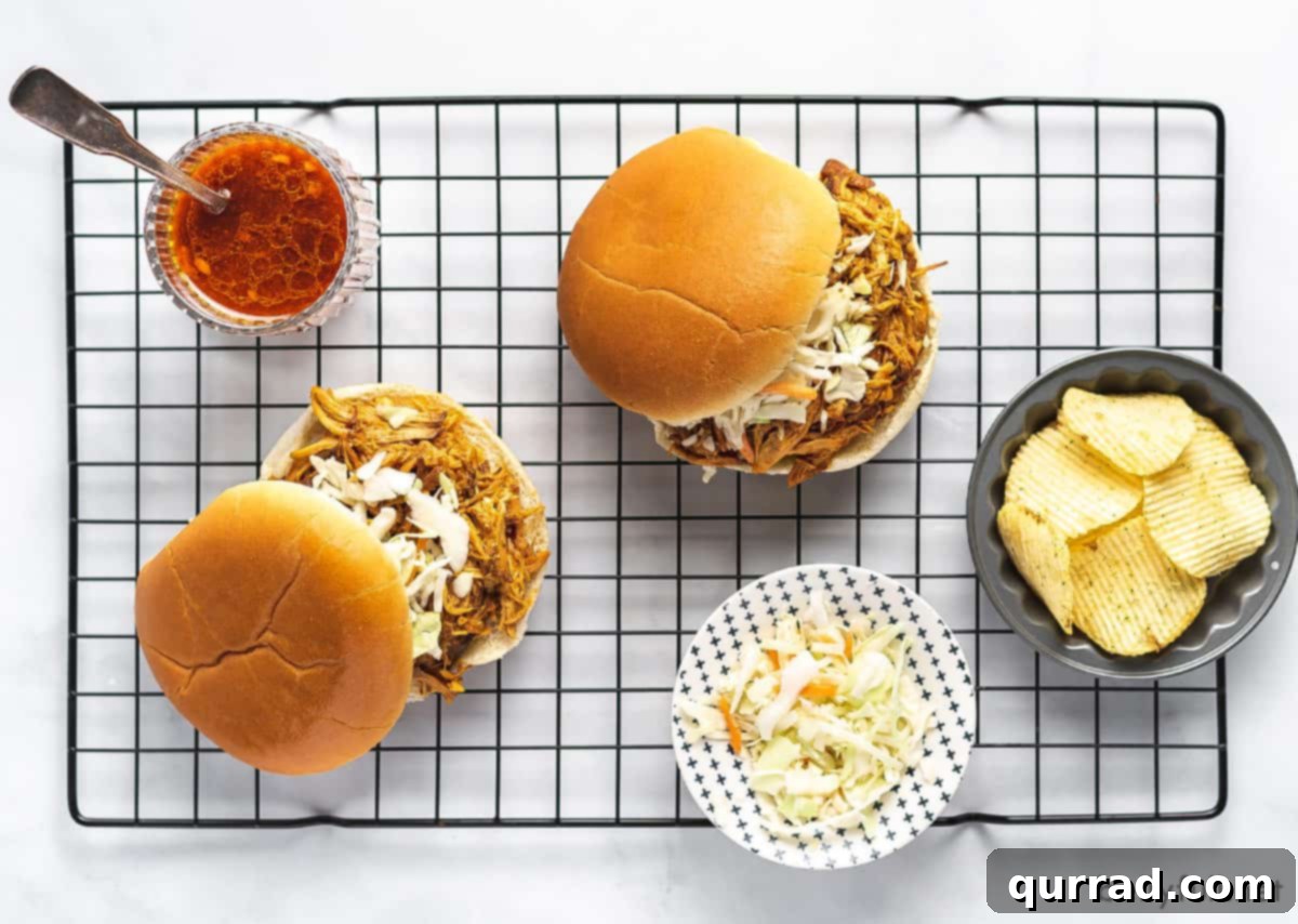 Set-and-Forget BBQ Chicken 5 Two mouth-watering BBQ chicken sandwiches, piled high with shredded chicken and nestled on a cooling rack, ready to serve.