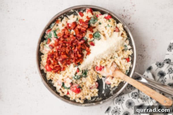 Crispy bacon pieces and Parmesan cheese mixed into the BLT pasta in a pan
