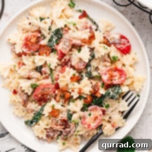 Overhead view of creamy BLT Pasta in a white dish with a fork, ready to be served.