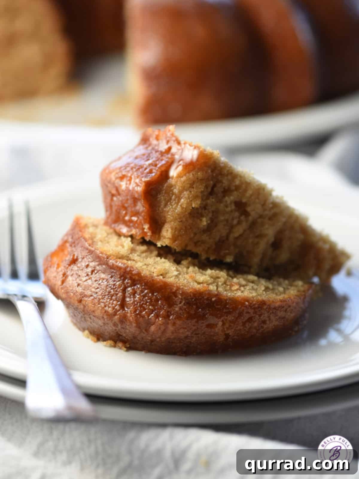 Two generous slices of homemade cinnamon cake, perfectly stacked on a pristine white plate, promising warmth and deliciousness.