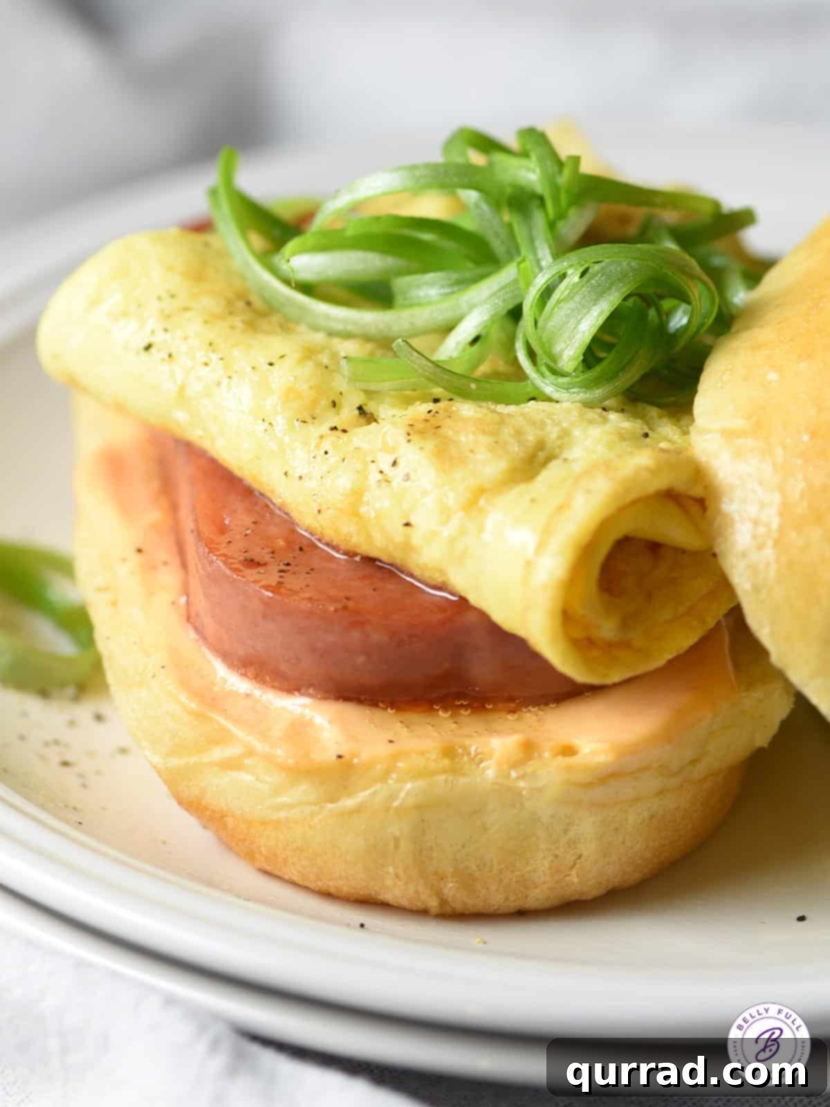 Savory SPAM Sunrise Sandwich 4 Open-faced SPAM breakfast sandwich showing a thick slice of fried SPAM, fluffy egg omelet, and delicate scallion curls layered on a toasted Hawaiian roll with a generous spread.