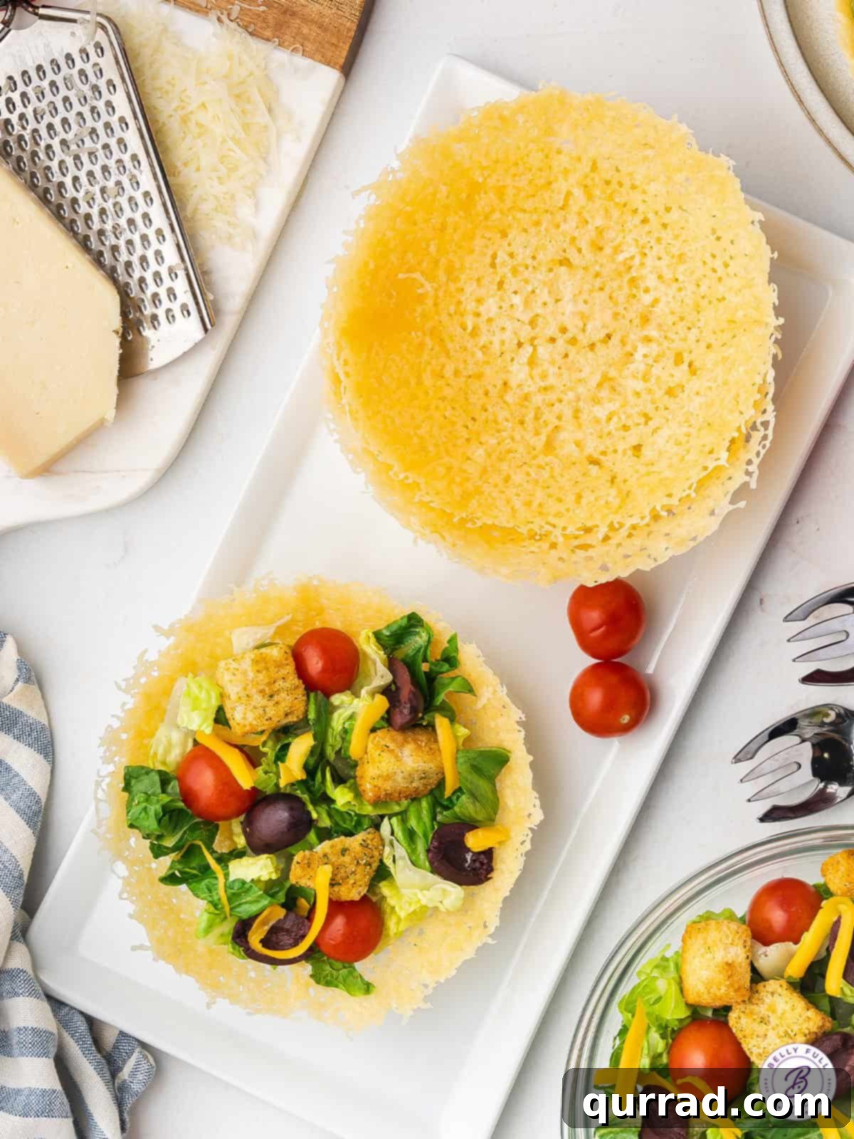Edible Parmesan Bowls 3 A perfectly formed Parmesan crisp bowl filled generously with a fresh, vibrant green salad, showcasing its appealing presentation and the crispy texture of the cheese. The salad includes various greens, tomatoes, and a light dressing.