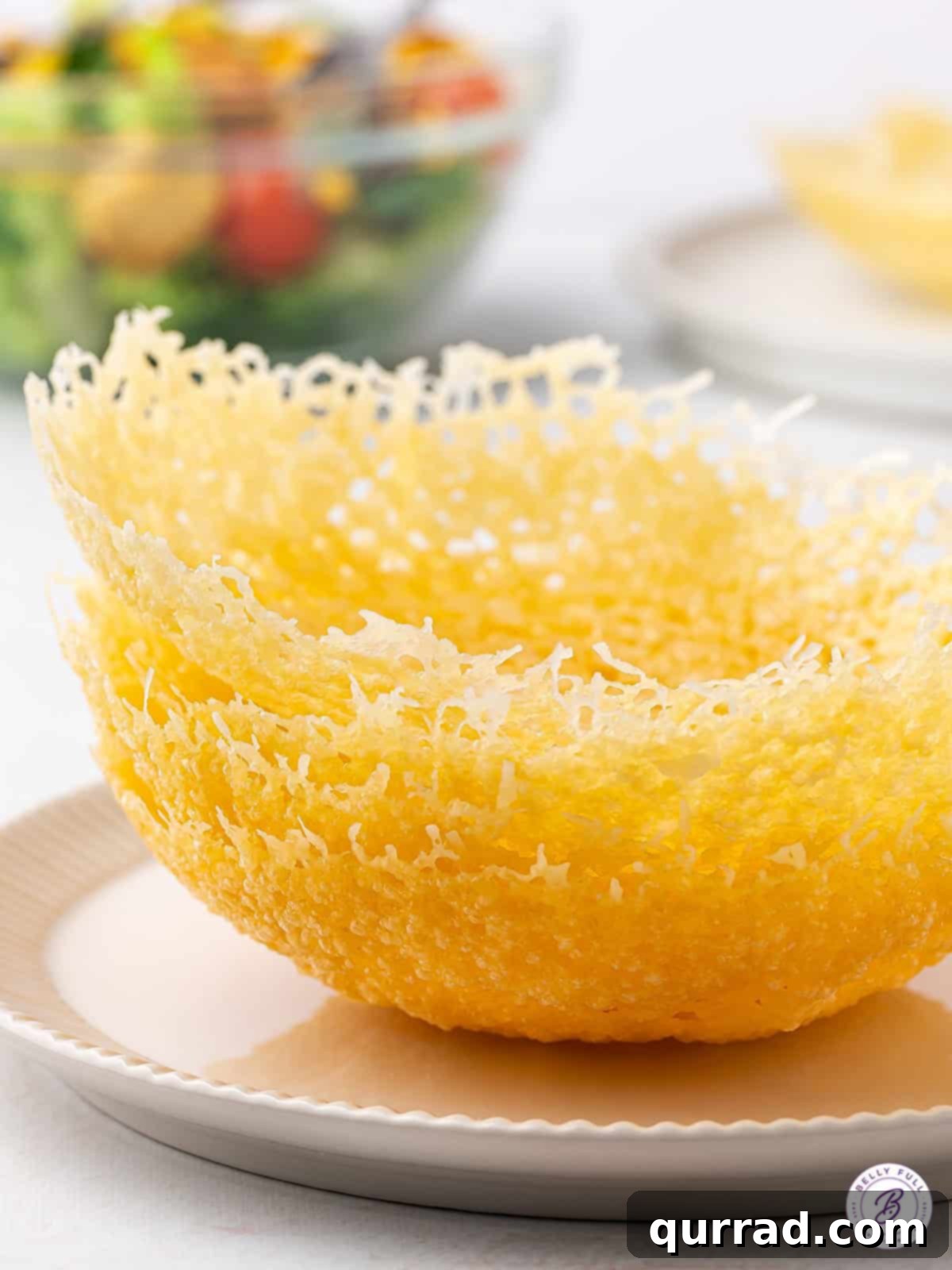 Edible Parmesan Bowls 5 Four perfectly golden-brown Parmesan cheese bowls stacked gracefully, highlighting their consistent crispness and readiness for culinary endeavors. The light plays off their textured surface, emphasizing their delicious appeal.