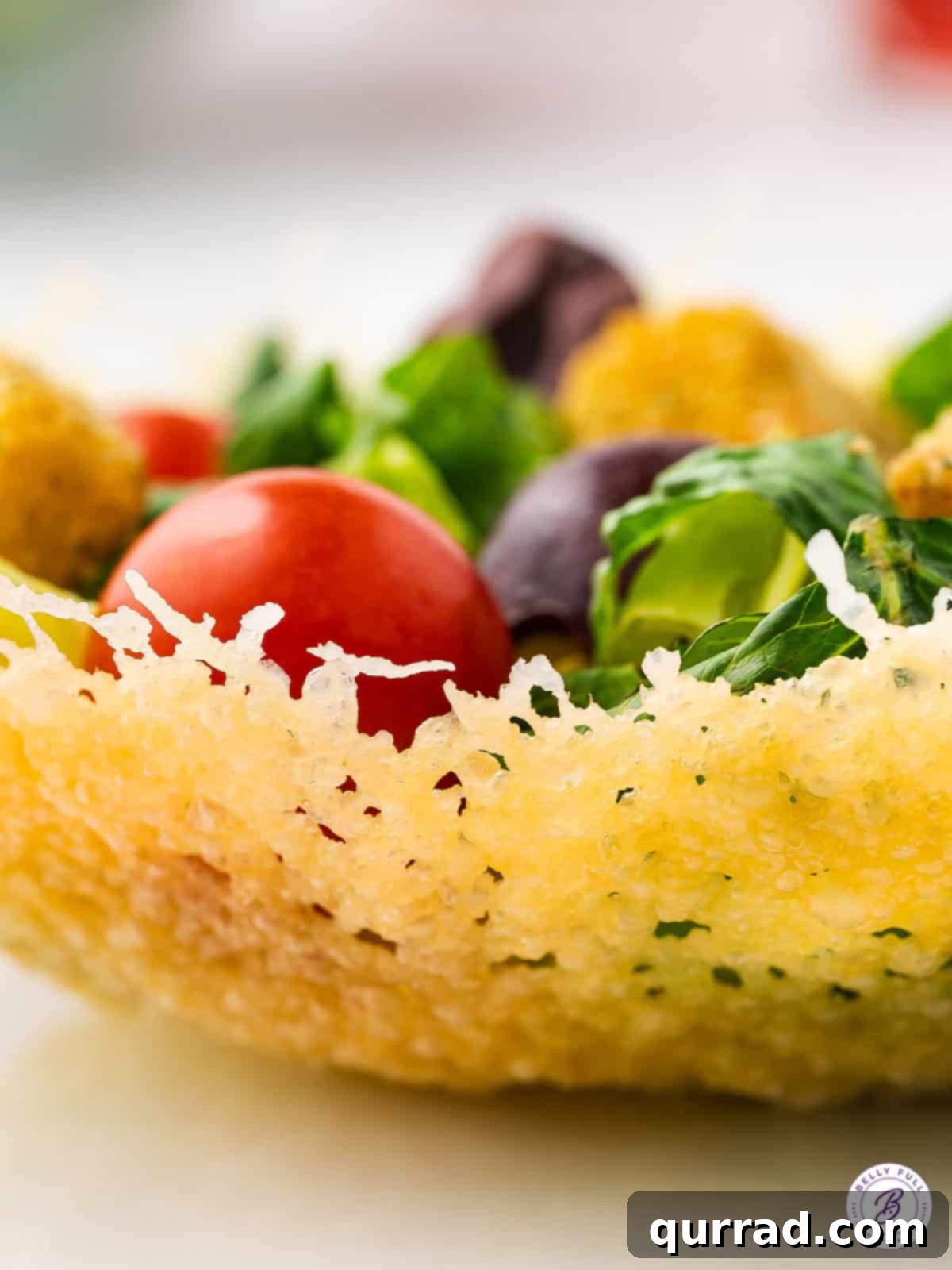Edible Parmesan Bowls 6 A beautifully crafted Parmesan cheese bowl generously filled with a vibrant, colorful salad, featuring various greens, cherry tomatoes, and cucumber slices. The rich cheese bowl complements the fresh ingredients within.
