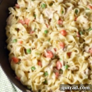 Close-up of creamy chicken pot pie noodles in a skillet, showcasing the rich sauce, tender chicken, and colorful vegetables.