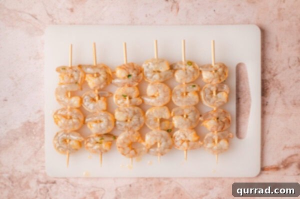 Raw shrimp skewers neatly arranged on a cutting board, ready for the grill.