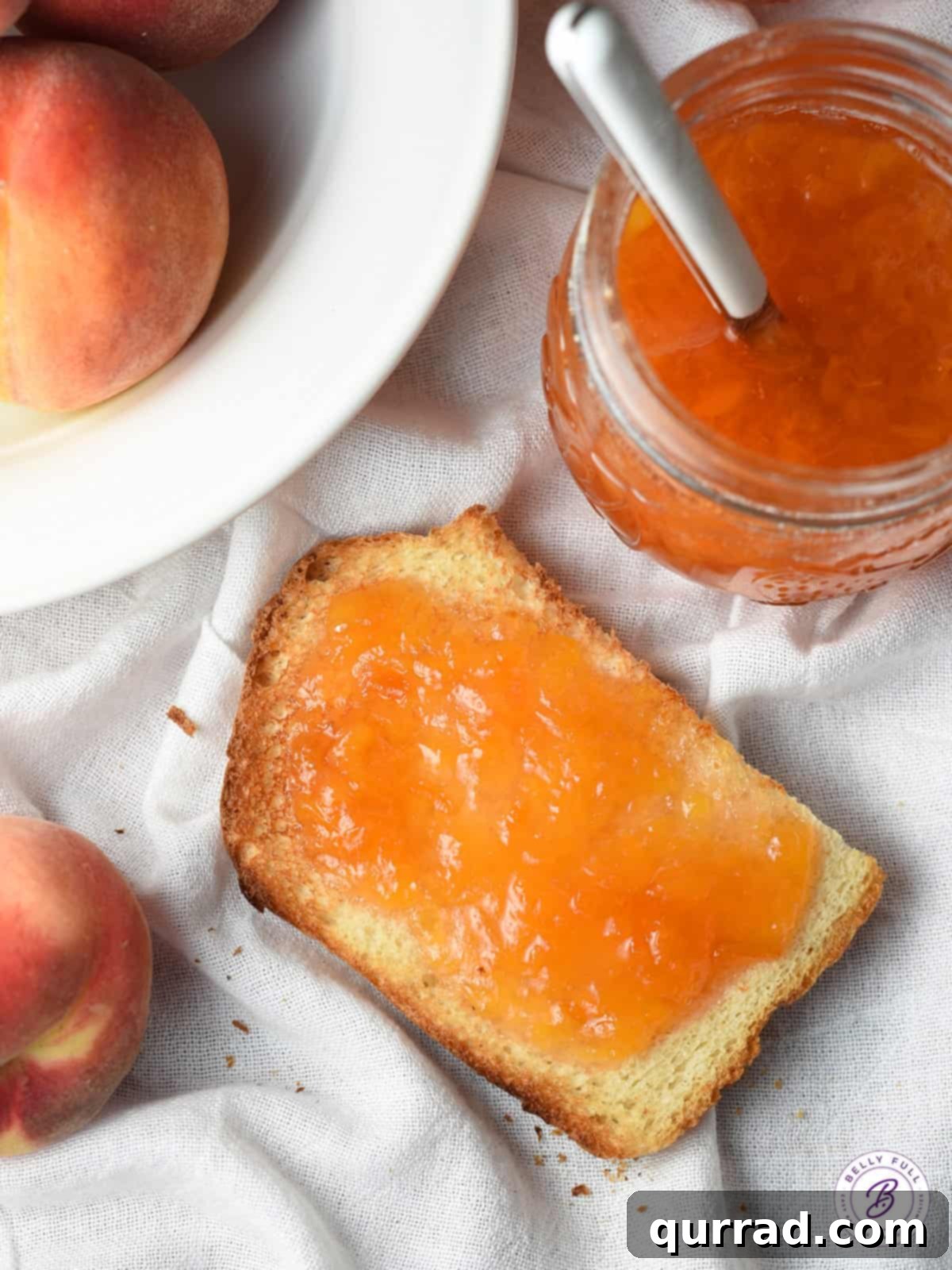 Golden Summer Peach Preserve 8 A close-up shot of golden peach jam spread generously on a slice of toast, with a full jar of jam and a spoon in the background, showcasing its delectable use.