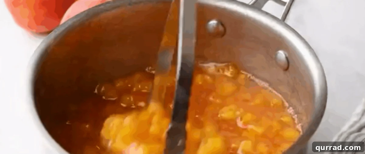 Golden Summer Peach Preserve 6 A potato masher being used to mash the cooked peach mixture directly in the pot, achieving the desired jam consistency.