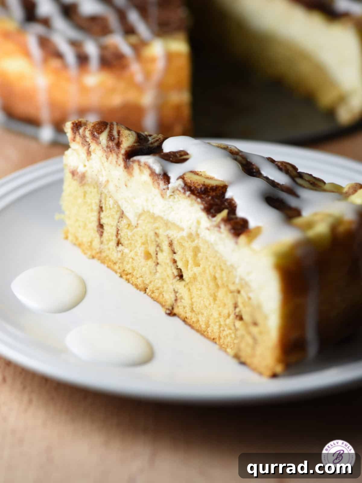 Cinnamon Swirl Cheesecake 3 side view of a perfectly sliced cinnamon roll cheesecake on a plate, showing the distinct layers and swirl