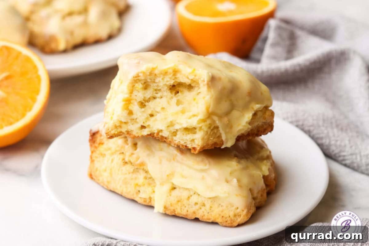 A Pair of Irresistible Orange Creamsicle Scones Two vibrant orange creamsicle scones, beautifully glazed and ready to be enjoyed, on a white plate