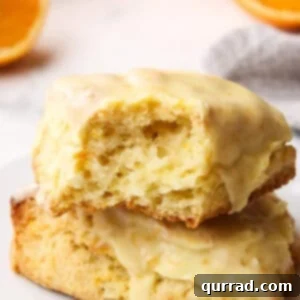Orange Creamsicle Scone with Flaky Interior Close up of two orange creamsicle scones on a plate, one with a bite missing to show the inside