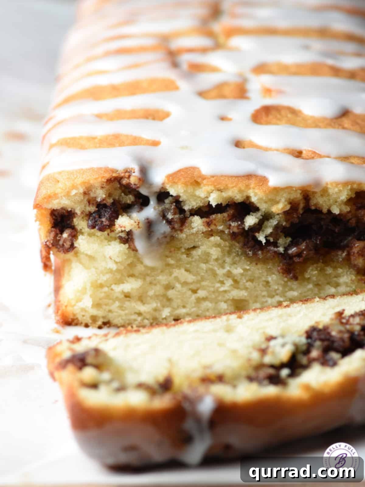 Whole cinnamon quick bread loaf topped with pecans and icing