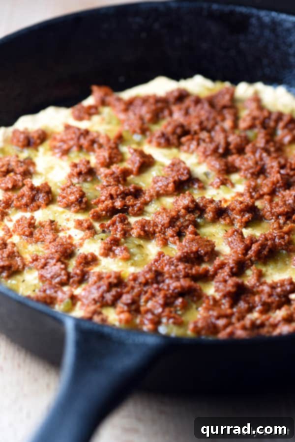 Chile Relleno Dip showing a distinct layer of browned pork chorizo nestled beneath a blanket of cheese