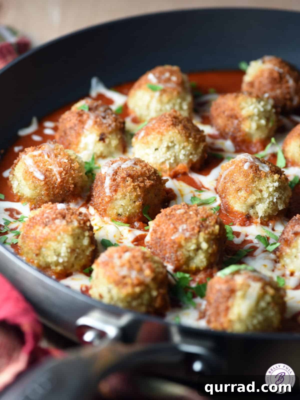 baked Chicken Parmesan Meatballs in a pan with bubbling tomato sauce and melted mozzarella