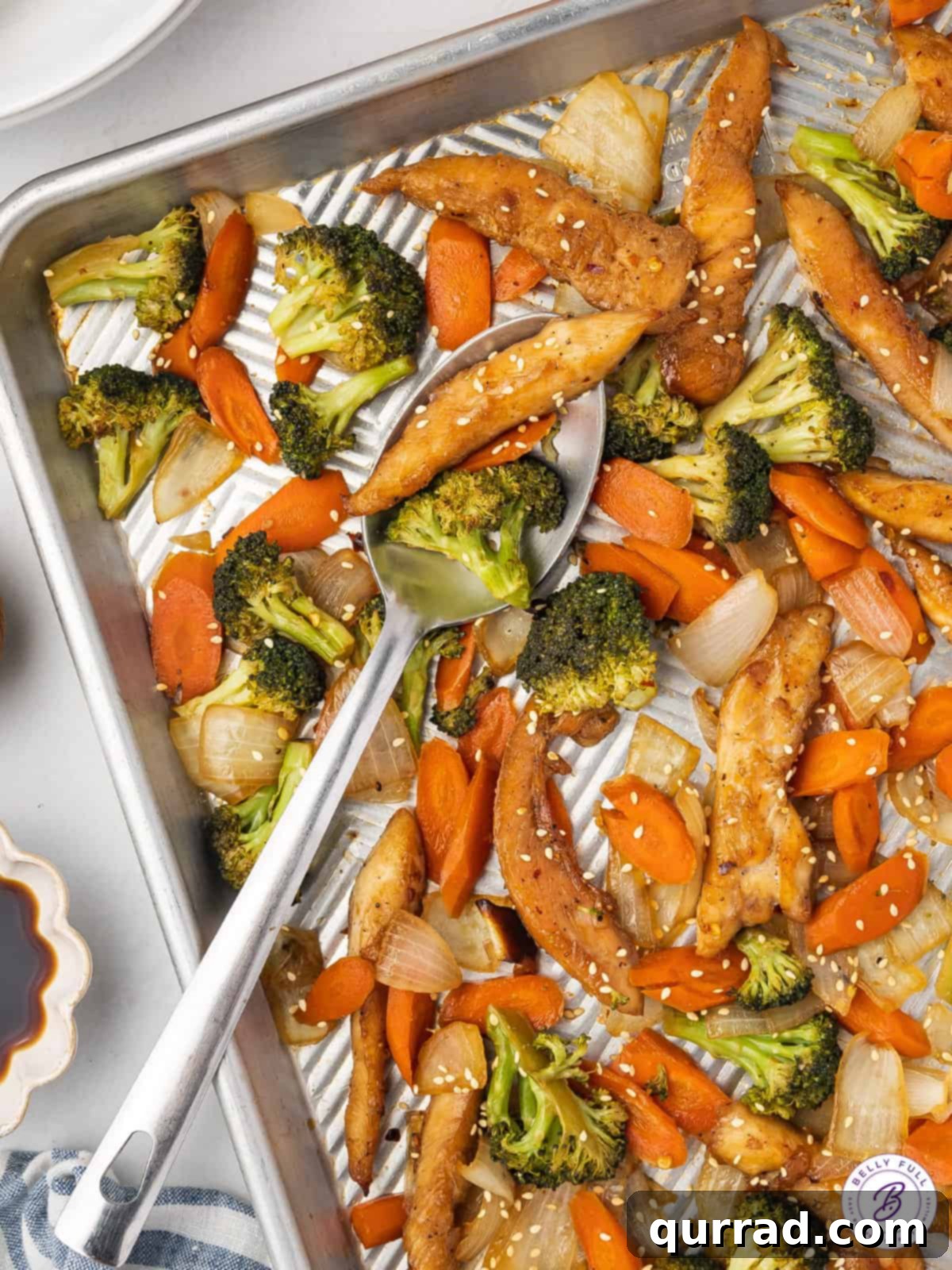 One-Pan Teriyaki Chicken and Veggies 3 Close-up shot of raw chicken tenders and fresh, brightly colored vegetables, including broccoli florets, sliced carrots, and chopped onions, arranged on a baking sheet before being tossed with sauce and roasted.