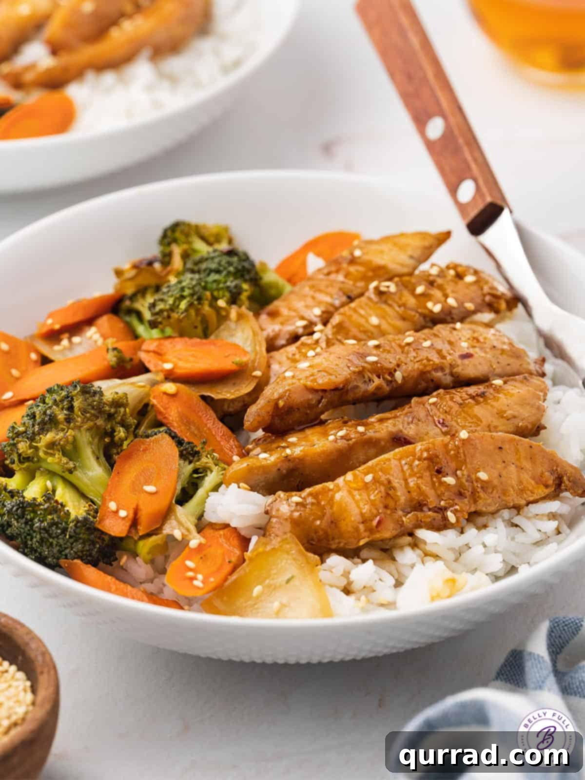 One-Pan Teriyaki Chicken and Veggies 4 A serving bowl filled with a generous portion of Sheet Pan Teriyaki Chicken and Vegetables over a bed of fluffy white rice, garnished with a sprinkle of sesame seeds, showcasing a delicious and complete meal.