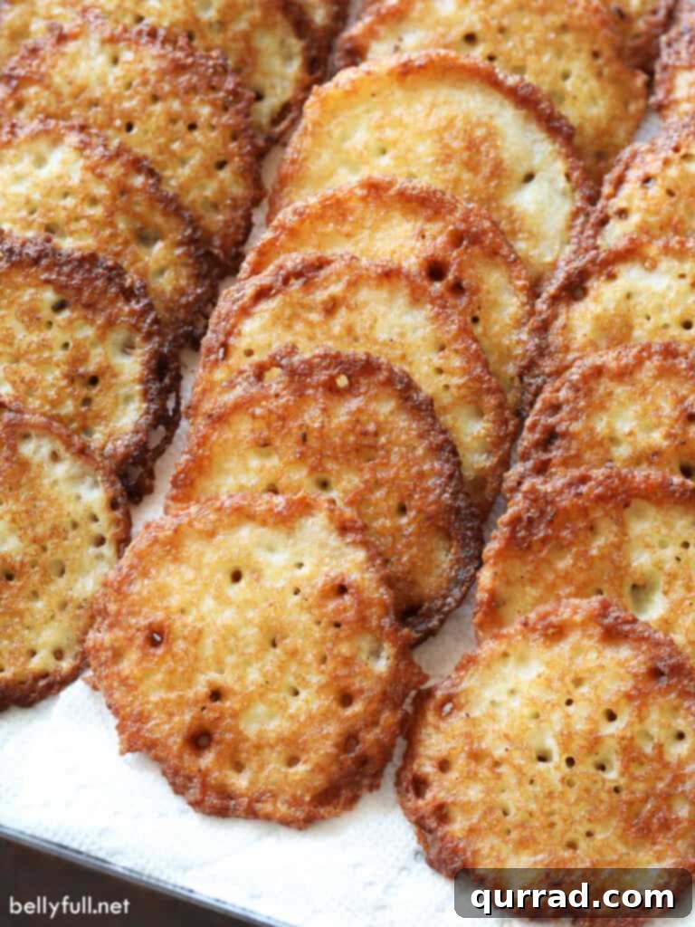 Crispy Potato Pancakes 2 Three rows of perfectly golden and fried potato latkes resting on a paper towel, ready to be served.