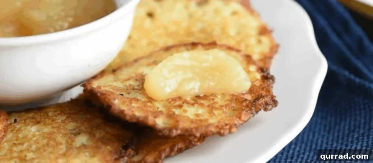 Crispy Potato Pancakes 8 Potato latkes served on a white plate with a side of applesauce.