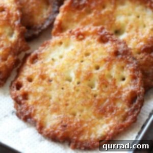 Close up of a golden and fried potato latke on a paper towel, highlighting its crispy texture.