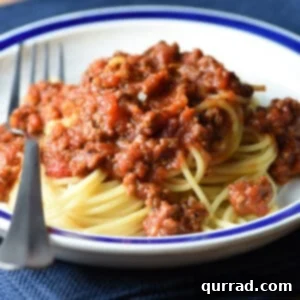 spaghetti meat sauce over a mound of cooked spaghetti