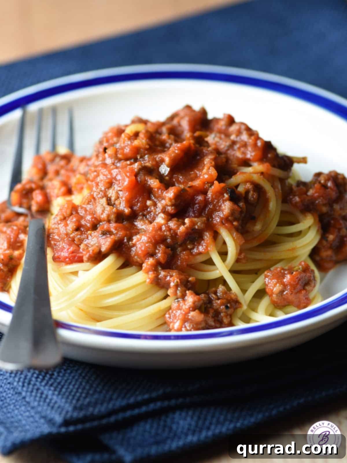 spaghetti meat sauce over a mound of cooked spaghetti